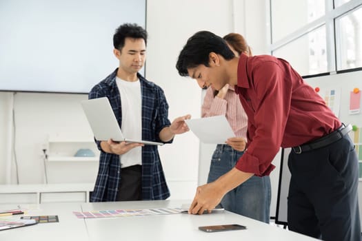 During a collaboration session, a team member evaluates color samples alongside colleagues, combining technology and creativity for effective design.