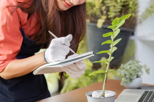 The gardener takes notes on her plant's growth, documenting important details to enhance her sustainable gardening practices.