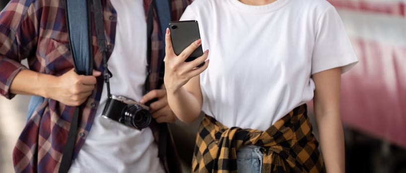 In a vibrant train station, a couple stands next to their bags as they admire travel memories captured on their smartphone, smiling and sharing stories.