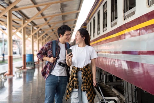 At the train station, a couple shares a joyful moment as they prepare for their trip, smiling at each other with excitement and anticipation.