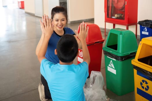 The child learns to categorize waste properly while enjoying a playful exchange with the instructor. Their smiles capture the essence of collaborative recycling education.