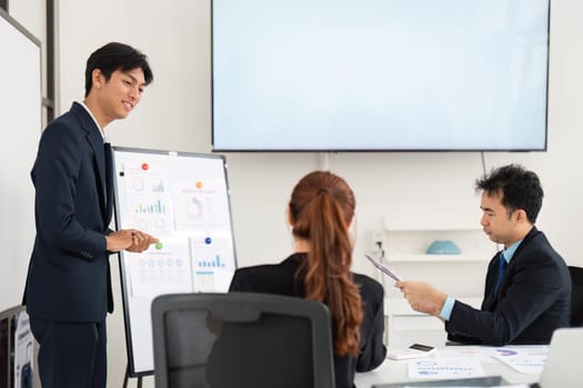 During a boardroom presentation, the young professional is engaging with team members, explaining data analysis while fostering a collaborative environment for strategic discussions.