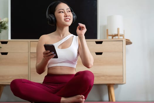 A yogi listens to uplifting music on her headphones during her workout, enhancing her experience and keeping her motivated and focused.