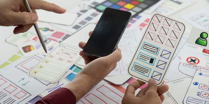 The team collaborates on wireframe designs, discussing user interface elements and ensuring a seamless user experience for their next mobile app project.