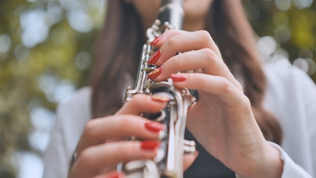 Musician's hands gripping clarinet, performing passionately amid verdant outdoor landscape, revealing artistic dedication