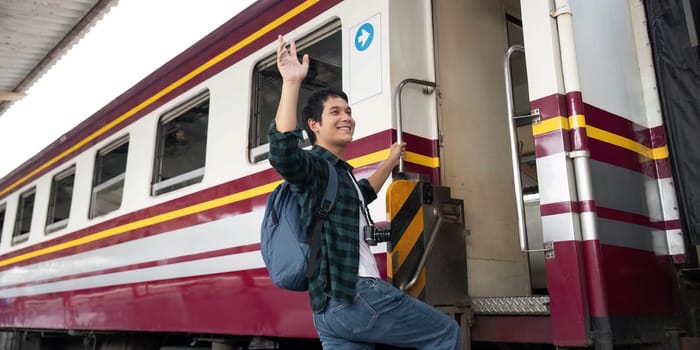 With a smile on his face, a young man climbs aboard a train, eager to begin his adventure. His backpack and camera reflect his enthusiasm for travel and exploration.
