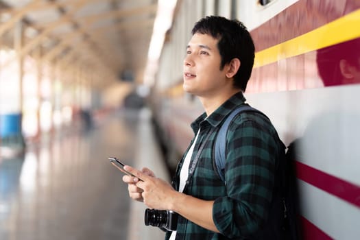 A young traveler leans against the train station wall, looking upward with anticipation, showcasing the moments of waiting that come with each adventure.