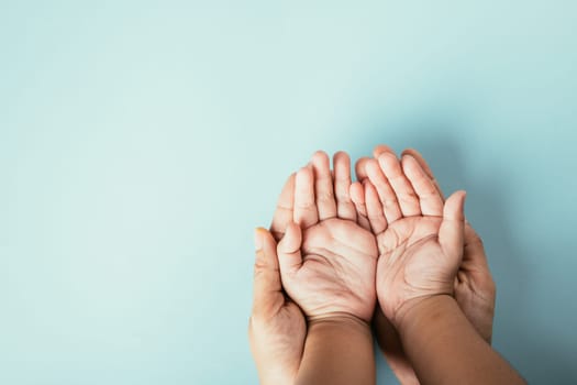 Close-up top view of family hands stacked isolated background. Parents and kid holding empty space together expressing support on Family and Parents Day.