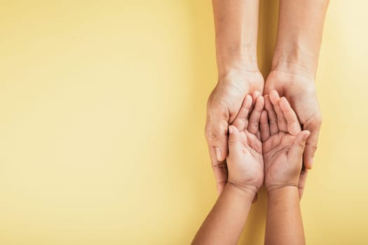 Studio shot, Close-up top view of family hands stacked isolated background. Parents and kid holding empty space together symbolizing support and love. Family and Parents Day concept.