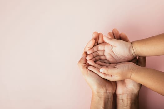 Top view of parents and kid holding empty hands together on a color background. Family day celebrating togetherness and support.