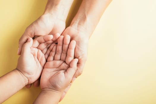 Close-up top view of family hands stacked on an isolated background in a studio shot. Parents and kids hold an empty space portraying support and love for Family and Parents Day.