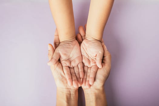 Celebrating family day, Top view of parents and kid holding empty hands together on a color background. Space for text.