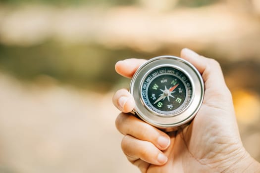 Traveler holds a compass in a park finding her way amidst confusion. The compass in her hand symbolizes guidance exploration and the journey to conquer defeat.