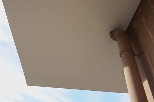 A close-up view of a ceiling and supporting column under clear blue skies.