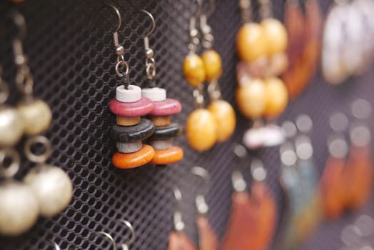 Various handmade earrings with vibrant colors are on display for sale.