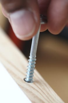 A person firmly secures a screw into wood to enhance stability.