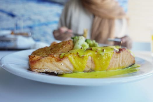 Tasty salmon fillet with sauce and veggies at a dining spot.