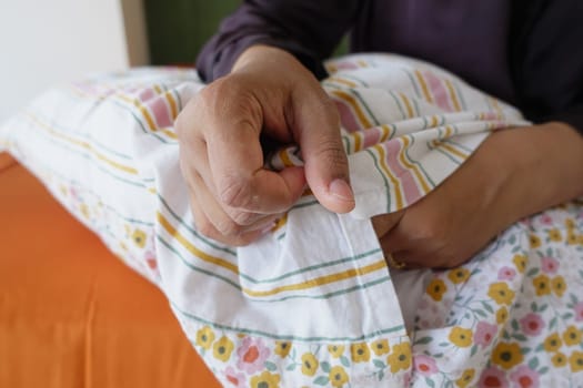 Individual is resting comfortably with hands gripping a pillow in bed.