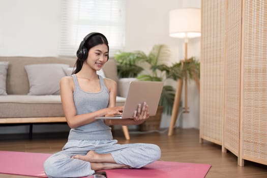 A focused woman engages with her laptop while balancing yoga practice, merging technology and mindfulness in her routine.