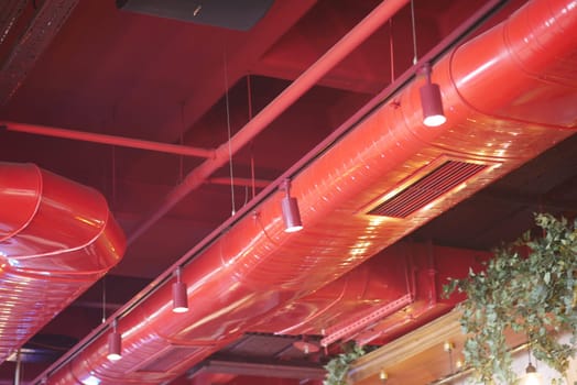 Bright red pipes and lights create a bold atmosphere in a contemporary setting.