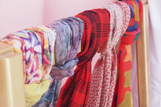 Various colorful scarves are displayed on a clothes rack indoors.
