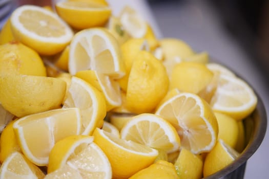 Slices of bright yellow lemons are neatly piled in a bowl, ready to use.