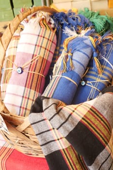 Vibrant woven textiles are neatly arranged in a basket at a local market.
