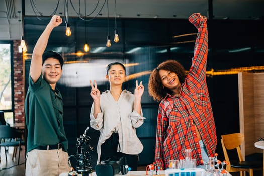 Happy students gathered in classroom excitedly raise hands to celebrate their successful learning in robotics class exploring futuristic robotic arm technology in domain of Innovation and Technology.
