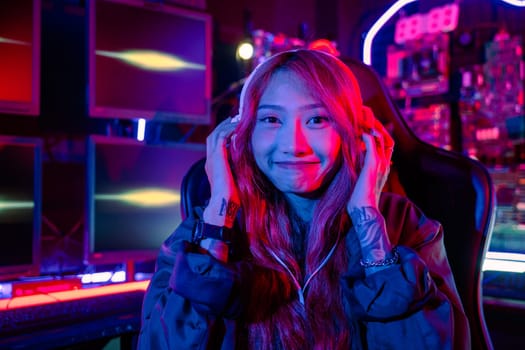Happy Gamer endeavor plays online video games tournament with computer neon light, Smiling young woman wearing gaming headphones intend to do playing live stream games online at home looking to camera