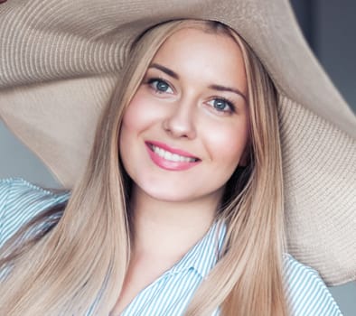 Woman, fashion and summer country charm, blonde beauty and elegance in wide brimmed beach hat. Feminine allure, timeless style and graceful glow. Smile, straw hat and blue striped blouse, natural lighting and effortless charm, fashion look idea