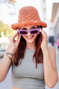 portrait of a happy young woman with hat smiling looking at camera over sunglasses, concept of youth