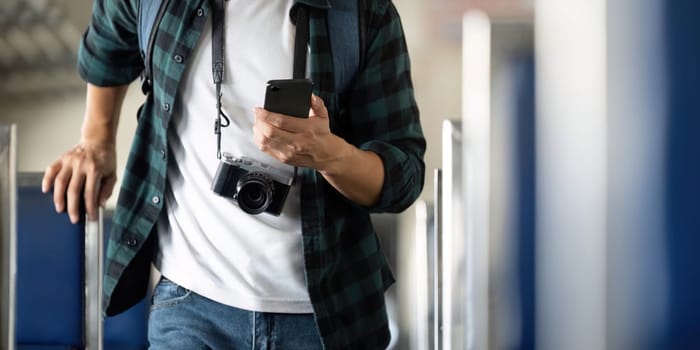 Capturing moments during his journey, a young man with a camera leans against a train seat, checking his phone for updates on his travels.