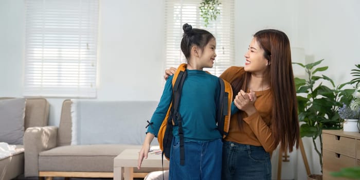 A cheerful mother assists her daughter in wearing her school backpack, creating an exciting and encouraging atmosphere as they prepare for school.