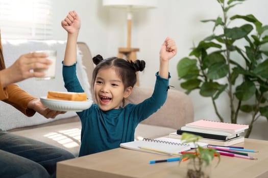 This joyful moment shows a girl celebrating snack time while engaging in her studies, emphasizing the balance of fun and learning.