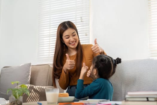 A mother and daughter share a fun moment, giving thumbs up, celebrating the joy of learning and achievements together.