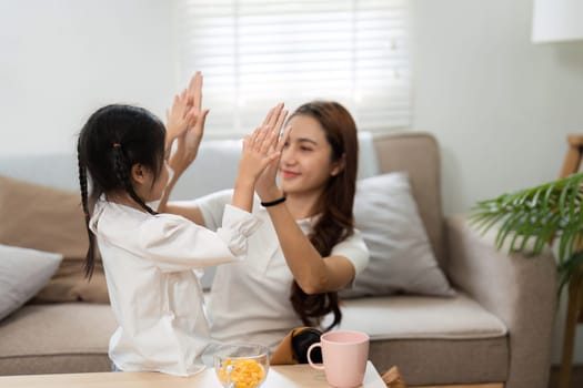 In a playful interaction, a mother engages with her daughter, fostering a joyful environment as they get ready for school together.