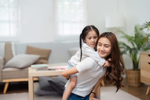 Before heading to school, a warm moment is shared as a mother gives her daughter a piggyback ride, highlighting the joy of togetherness.