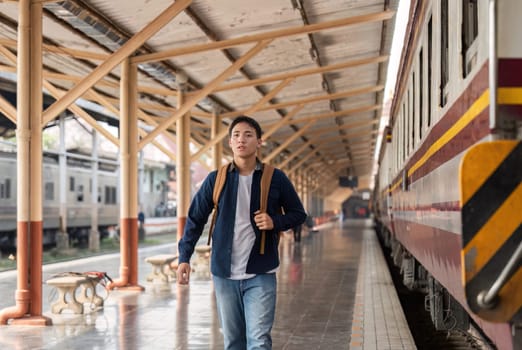A focused young man strides through the train station, eager to catch his train. His backpack signifies travel and exploration.
