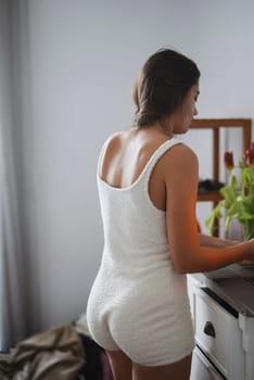A woman dressed in a soft and comfortable white outfit is captured in a serene and minimalistic indoor space