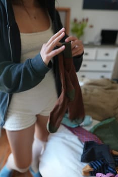 A person sorting clothes on a neatly made bed, showcasing a stylish, organized, and casual fashion aesthetic