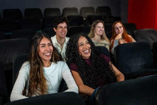 Friends laughing and enjoying a comedy movie at the cinema, sharing joyful moments together in a relaxed and fun atmosphere
