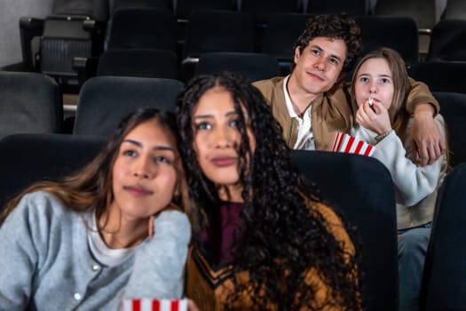 Group of friends enjoying a film at the movie theater, sharing popcorn and having fun together