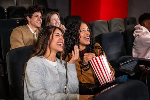 Friends enjoying a comedy film in a movie theater, laughing and sharing popcorn while soaking in the fun atmosphere of the evening