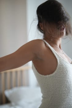 A woman dressed in a soft, comfortable outfit fully embraces the tranquility of a cozy, warm morning setting