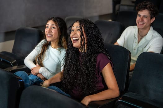Friends laughing and enjoying a movie at the cinema, sharing a moment of leisure and entertainment