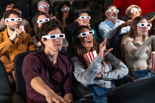 Diverse group of friends wearing 3d glasses, watching a movie at the cinema and eating popcorn, having fun together