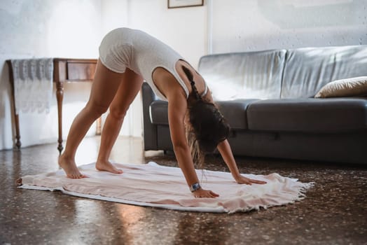 A woman is performing yoga in the comfort of her home, engaging in relaxation and fitness within a cozy atmosphere
