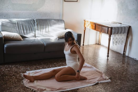 A woman practices yoga indoors, showcasing her flexibility and tranquility in a comfortable, inviting space