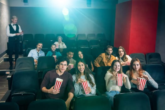 Diverse audience enjoying a film in a movie theater, eating popcorn and watching a movie projection