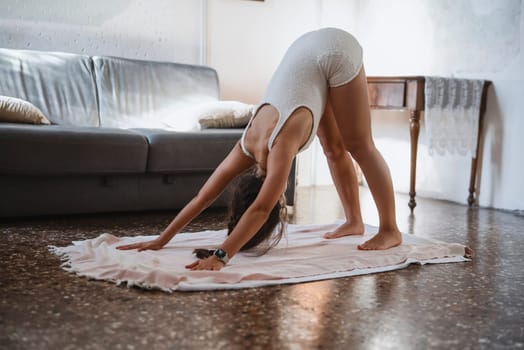 A woman performs the Downward Dog pose, showcasing flexibility and wellness in a serene home setting.